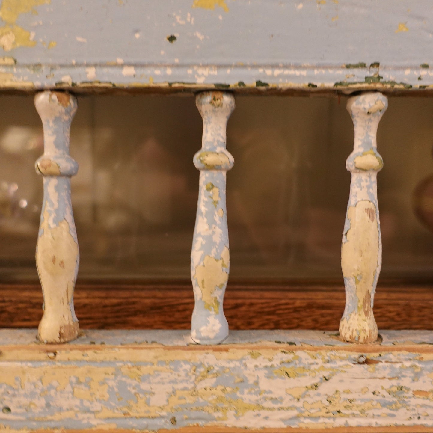 Close-up of ornate wooden legs with peeling paint on a distressed surface.