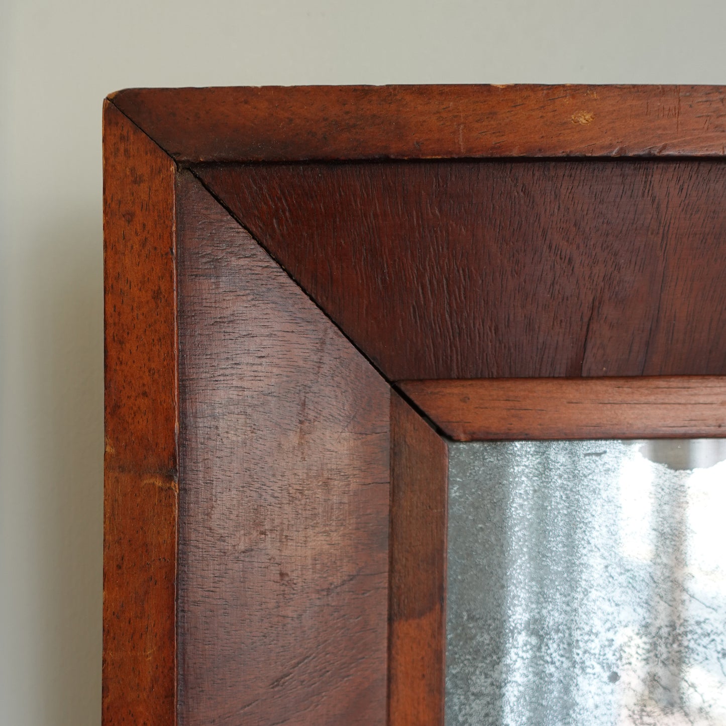 Close-up of a wooden frame corner with a reflective surface.