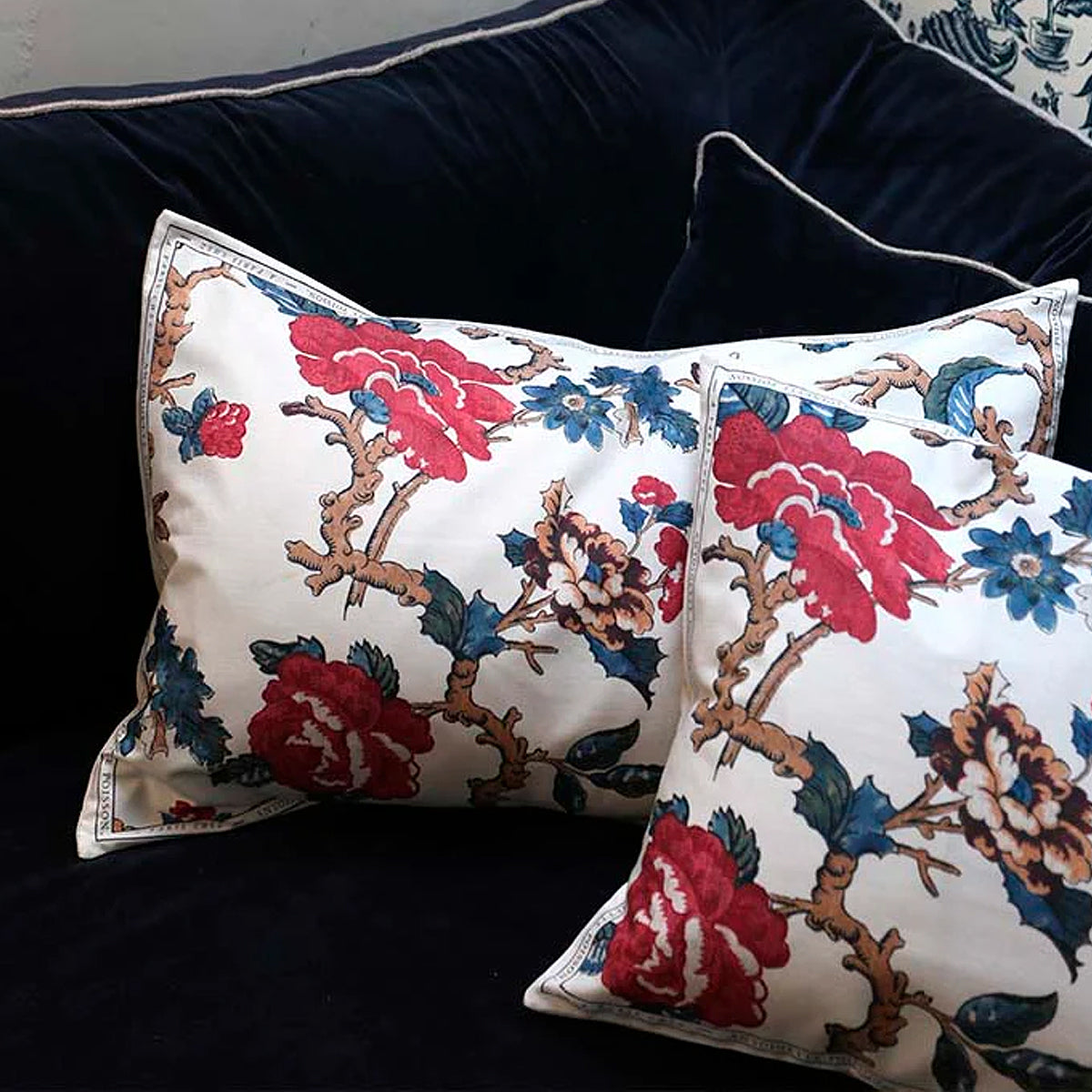 Decorative pillows with floral patterns on a dark blue sofa.
