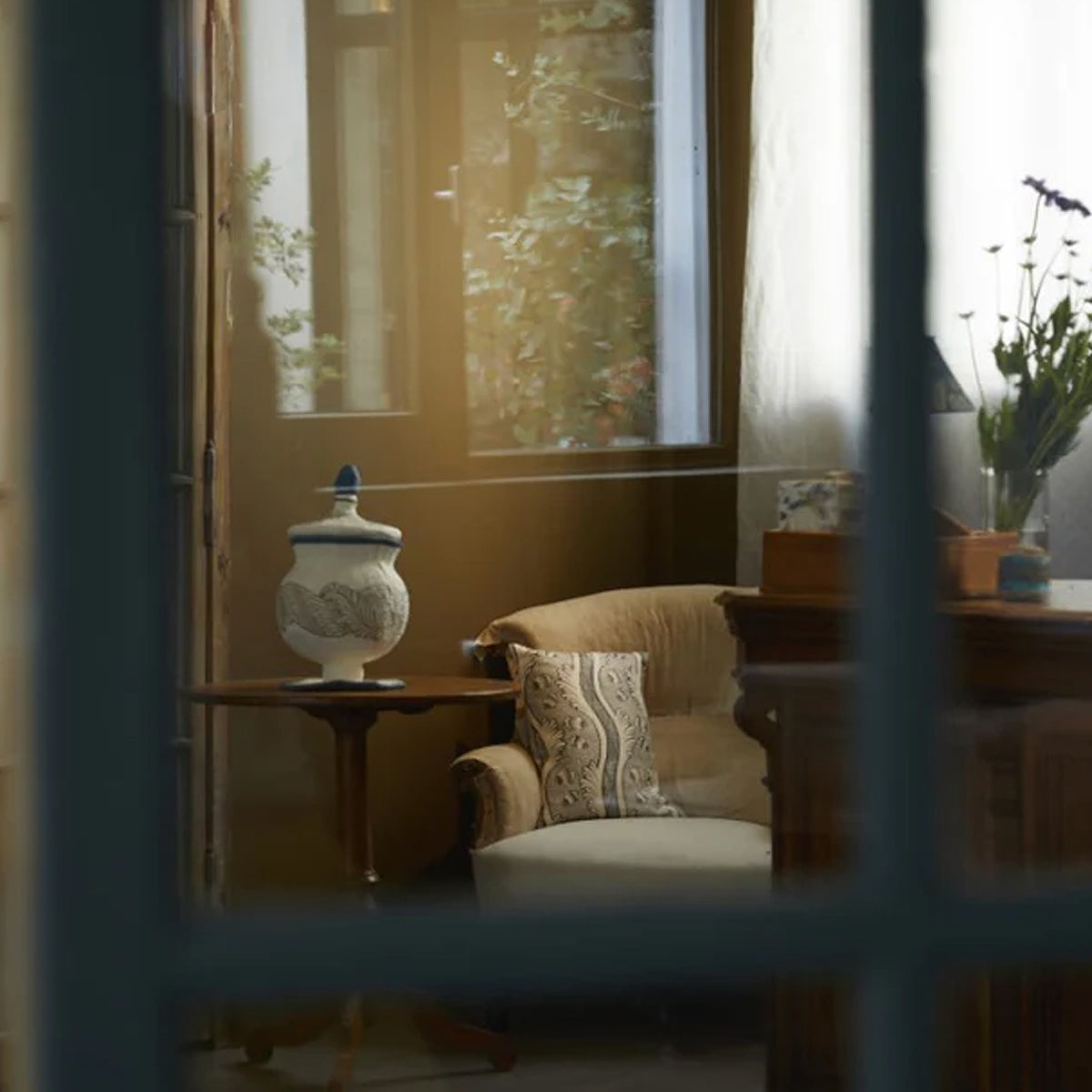 Cozy living room with a beige armchair, decorative pillows, and a side table with a lamp.